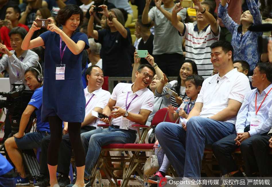 姚沁蕾坐在爸爸姚明身旁，双手扶着座椅，眼睛专注地看着球场方向，扎着马尾辫的背影显得既可爱又认真