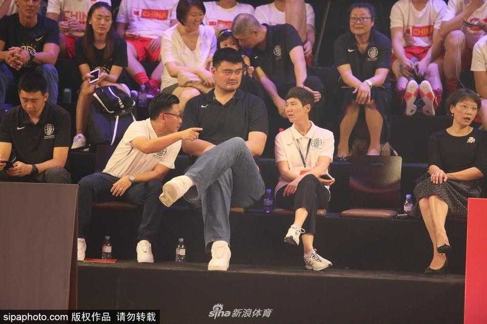 姚明手持篮球仔细观察，身旁的奖杯熠熠生辉，仿佛在传递着对草根冠军的致敬