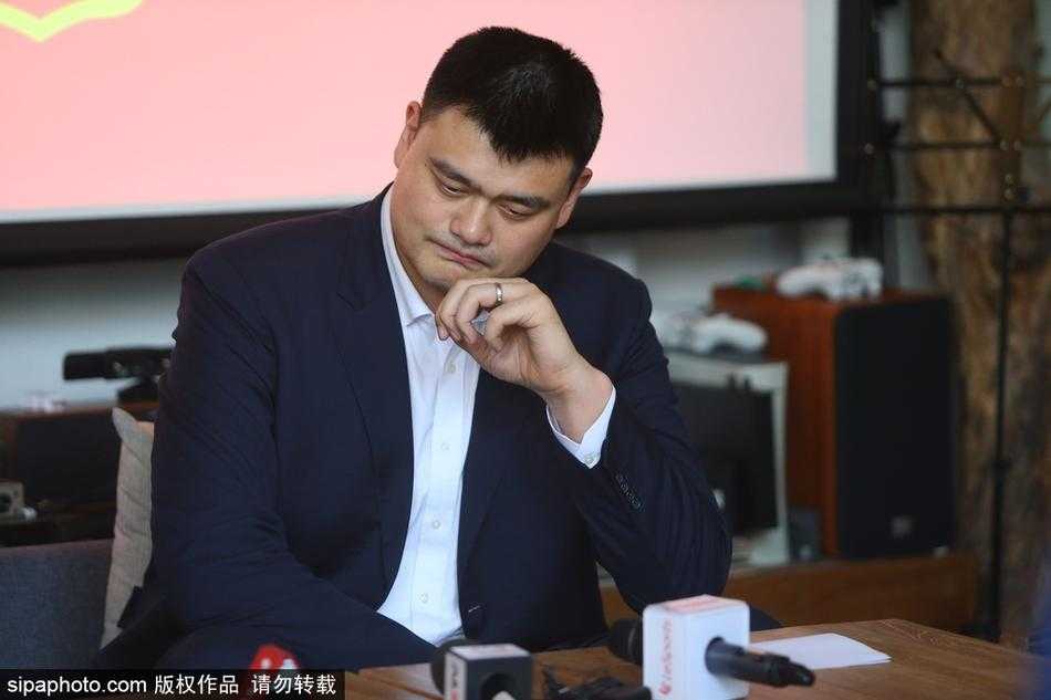 姚明在活动现场耐心倾听记者的提问，他的眼神专注而诚恳，周围摆放着简约的咖啡馆桌椅，透露出这次交流非正式的轻松基调。