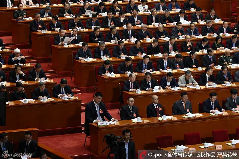 在座无虚席的万人礼堂中，姚明微微侧身，专注地与身旁的委员交换看法，他高出座位一截的身影在人群中极为醒目，周围委员或侧耳倾听或点头示意，氛围专注而融洽。