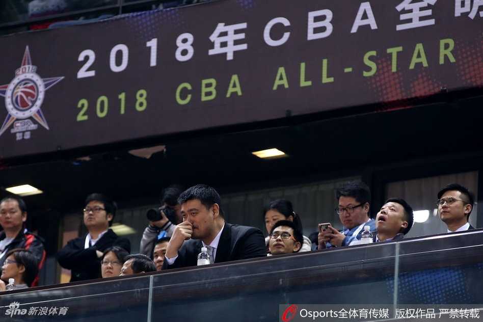 姚明扭头与身旁的友人窃窃私语，脸上的表情带着一丝难以置信，仿佛在说：“刚才这球居然没进？现在的小年轻啊。”