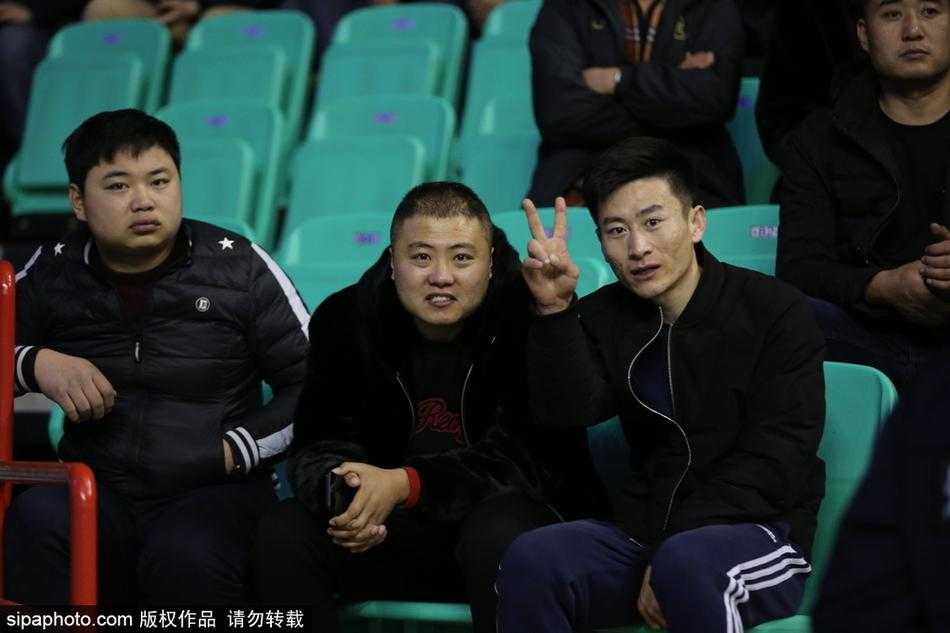 看台过道上，几位穿着奢华貂皮大衣的球迷并肩而立，其中一位女性球迷正挥手欢呼，厚重的皮草难掩她此刻因为主队领先而迸发的激情。