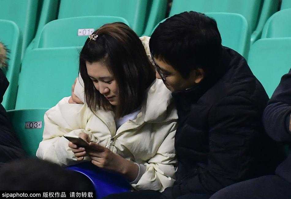 男球迷在万众瞩目下深情亲吻他的女友，女孩闭着眼沉浸在幸福中，背景是模糊的看台和CBA的广告牌，这一刻体育竞技的残酷被爱情的甜蜜温柔化解。