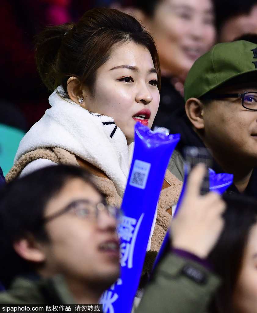 这位气质清冷的美女球迷戴着白色毛线帽，在人群中静静回眸。她深邃的眼眸和精致的侧颜在嘈杂的看台上形成一道独特的风景，仿佛周遭的喧嚣都与她无关，她只专注于自己眼中的那片赛场。