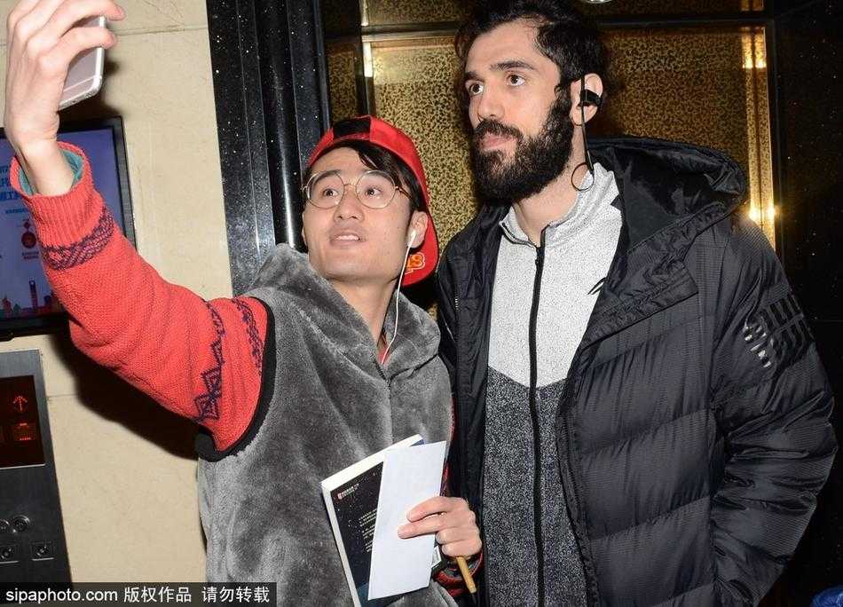 从高空俯瞰酒店大堂，同曦队球员们被热情的浪潮包围，他们或签名或合影，黑色的队服在人群中格外醒目，整个大堂因为这群篮球健儿的到来而充满了生机与活力。