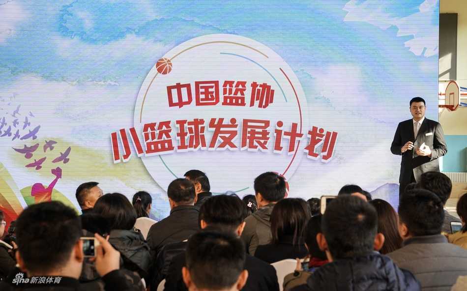 几位领导嘉宾站在摆满捐赠小篮球和篮架的桌子后，准备将这些为孩子们量身定做的体育器材送到学校手中。