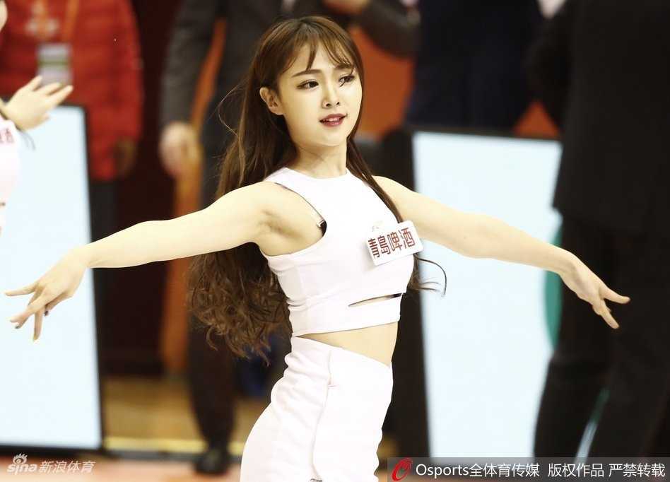 身着校园风短裙的啦啦队女孩，在体育馆看台上回眸一笑，眼神清澈动人