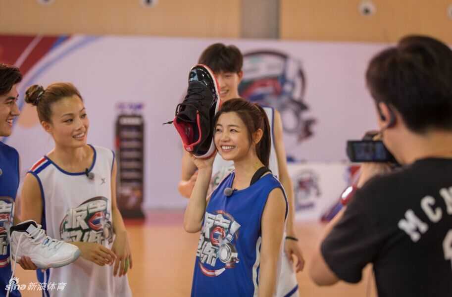 阿联小心翼翼地将陈妍希托举到篮筐高度，助她轻触篮筐圆梦