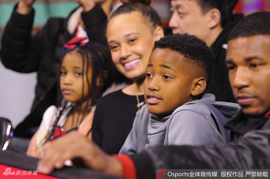 妻子依偎在巴斯身旁，两人目光交汇中满是爱意，周围球迷的喧嚣仿佛都成了他们幸福画面的背景音。