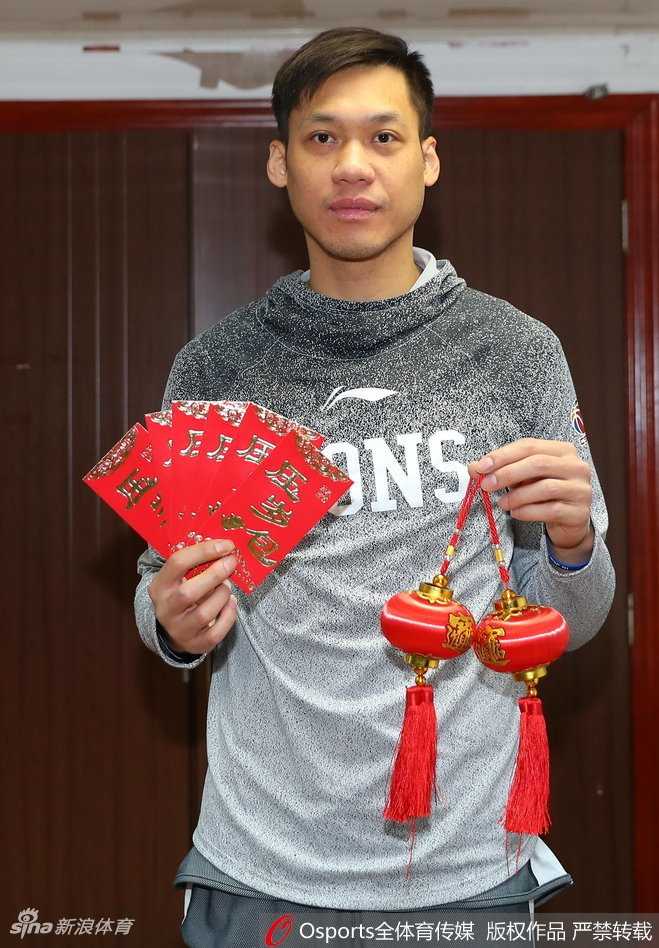 广厦后卫凝视镜头，双手稳稳展开一幅写有吉祥话的春联，眼神中透露出对球迷的深情祝福。