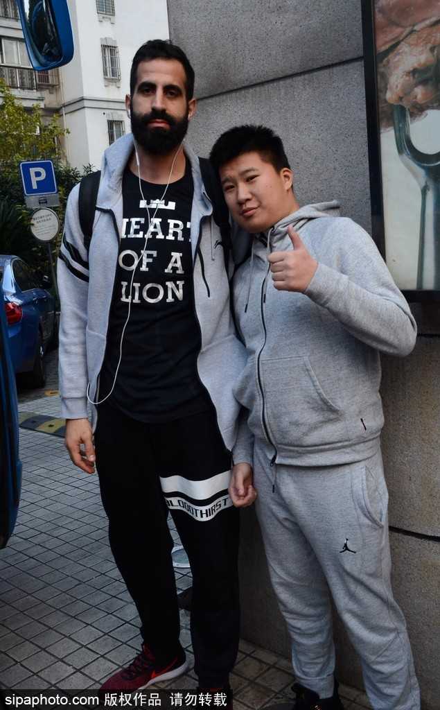 广州龙狮队抵沪,外援亲和力十足与球迷热情互动 汉斯布鲁在酒店大堂为球迷耐心签名,眼神专注,身后球迷兴奋地展示签名战利品