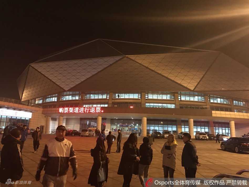 当篮球架遇见演唱会舞台:一场因“跨界”而取消的CBA比赛 体育馆入口的玻璃门上,贴着一张临时打印的白色A4纸通知,上面清晰地写着关于本场比赛因故改期的告示和退票指引,透过玻璃门能看到馆内仍然灯火通明,却无人入场。