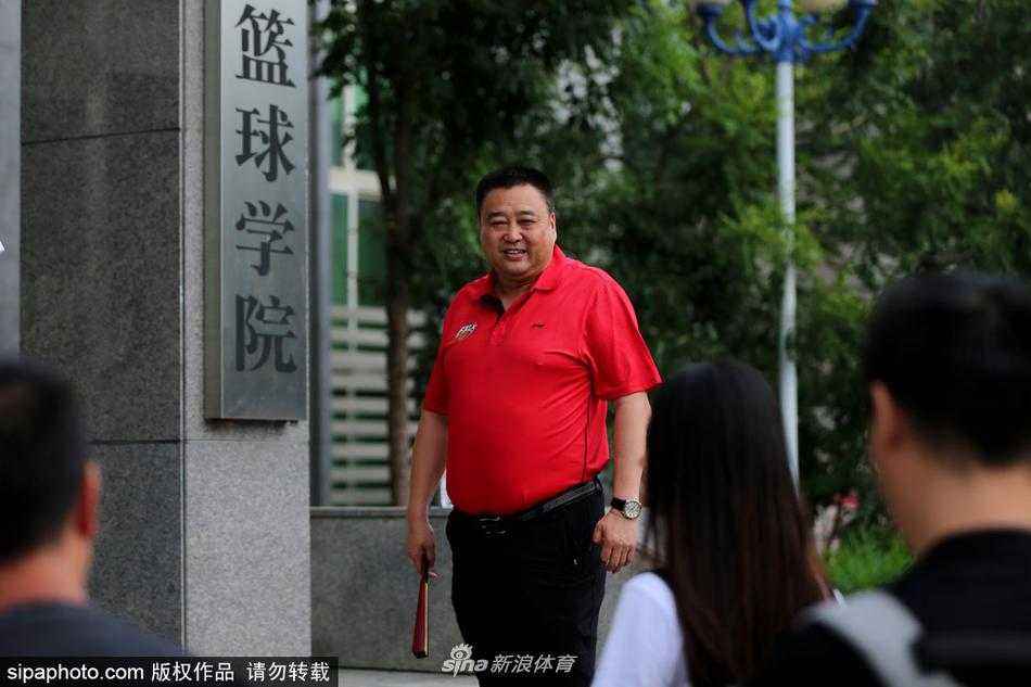 略显陈旧的训练馆角落，摆放着一排排训练用的篮球，皮面已被无数次拍打磨得光滑发亮，背景是墙上悬挂的“从这里起飞”红色横幅，仿佛在默默记录着无数少年从这里走向全国赛场的足迹。