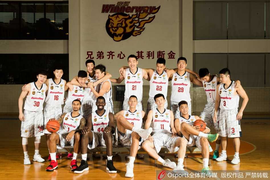 广东宏远队全体成员在摄影棚内整齐排列，球员们身着新赛季战袍，目光如炬看向镜头，易建联居中稳稳站立，整支队伍气场全开，展现王者之师的威严与团结。