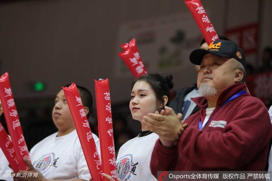 新疆男篮主场靓丽风景线 美女球迷激情助阵点燃红山 这位美女球迷手里拿着加油棒,脸上贴着新疆队的贴纸,正和身边的朋友交流着场上的局势,显得非常专业。