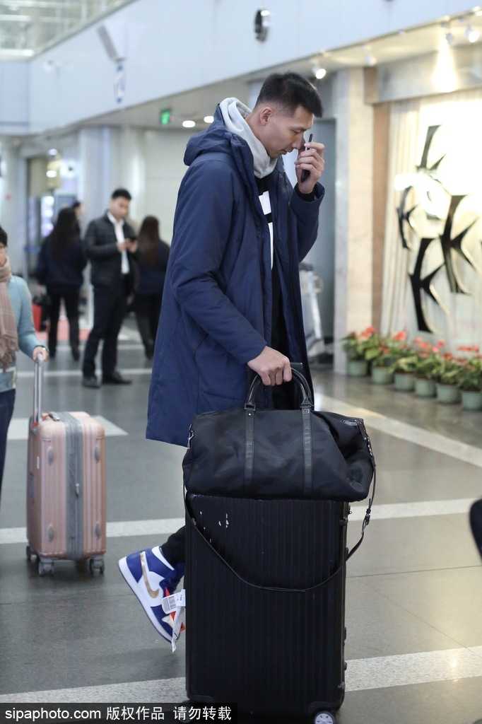 易建联身穿深色潮流外套搭配个性背包，在机场通道中回眸一瞥，眼神中既有运动员的坚毅又不失时尚达人的洒脱