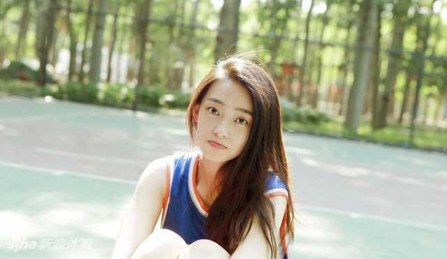 王艺诺身穿宽松球衣坐在泳池边，侧身回眸露出嫣然一笑，眼神中带着一丝傲娇与俏皮，复古色调下显得既优雅又充满邻家女孩的亲切感。