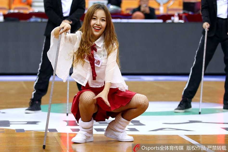 近景镜头下，一名篮球宝贝对着镜头露出甜美微笑，额头上的汗珠在灯光下闪闪发亮