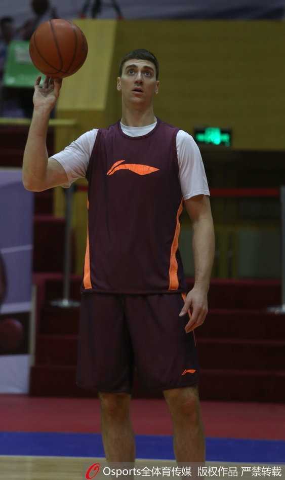 主教练手持战术板，神情严肃地向围坐一圈的队员们布置最后一攻的战术，队员们聚精会神地聆听。