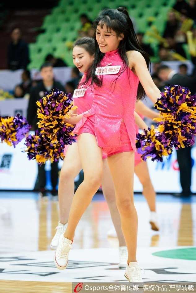 特写镜头中，一位篮球宝贝手持彩球，眼神坚定地看向前方，精致的妆容和闪耀的服饰让她在球场灯光下格外夺目。