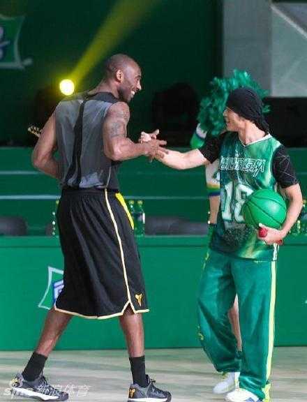 周杰伦绑着标志性的发带，嘴角微微上扬，露出那副有点酷又有点坏的笑容，即使在激烈的拼抢中，他也要保持绝对的帅气。