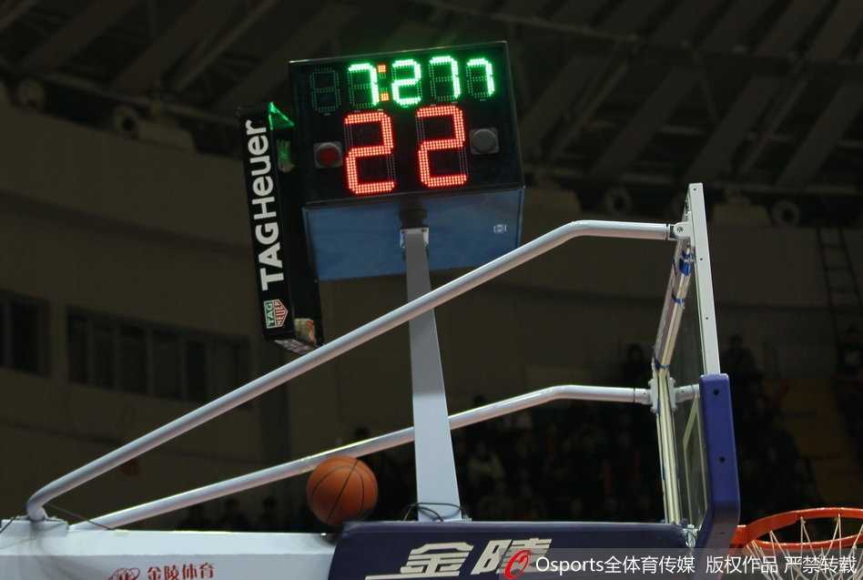 红山体育馆内灯火通明，广东宏远与新疆广汇的球员在场上激烈拼抢，客队替补席后方被砸裂的记分牌外壳清晰可见，仿佛在诉说着比赛的惨烈