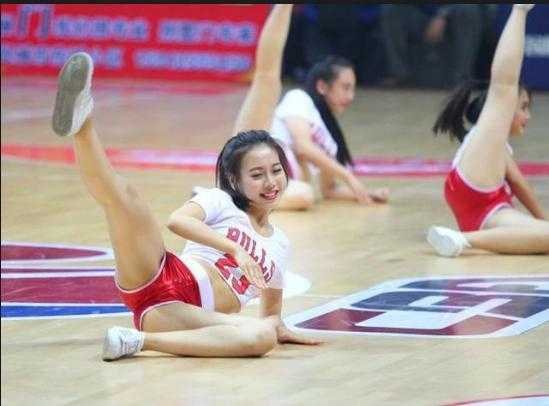 篮球宝贝惊艳一字马的背后,是你看不到的台下十年功 近景镜头下,一位篮球宝贝正在侧身展示一字马,优美的身体线条和紧绷的脚尖,显示出深厚的舞蹈功底,背景是模糊的观众席,仿佛整个赛场都在为她的专注而静止。