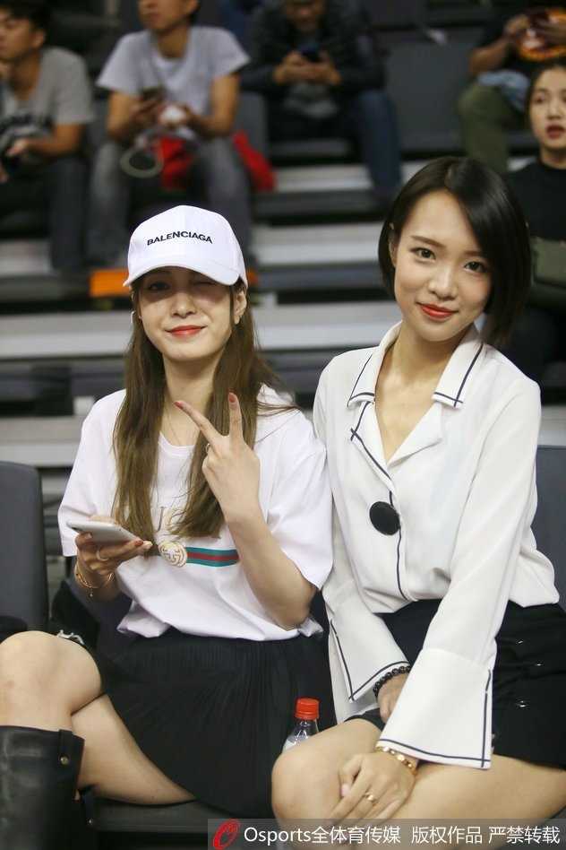 粤疆大战场边的那一抹温柔亮色 一位气质温婉的女球迷坐在看台前排,背景是激烈的比赛画面,她仿佛沉浸在自己的篮球世界中,温润如玉。