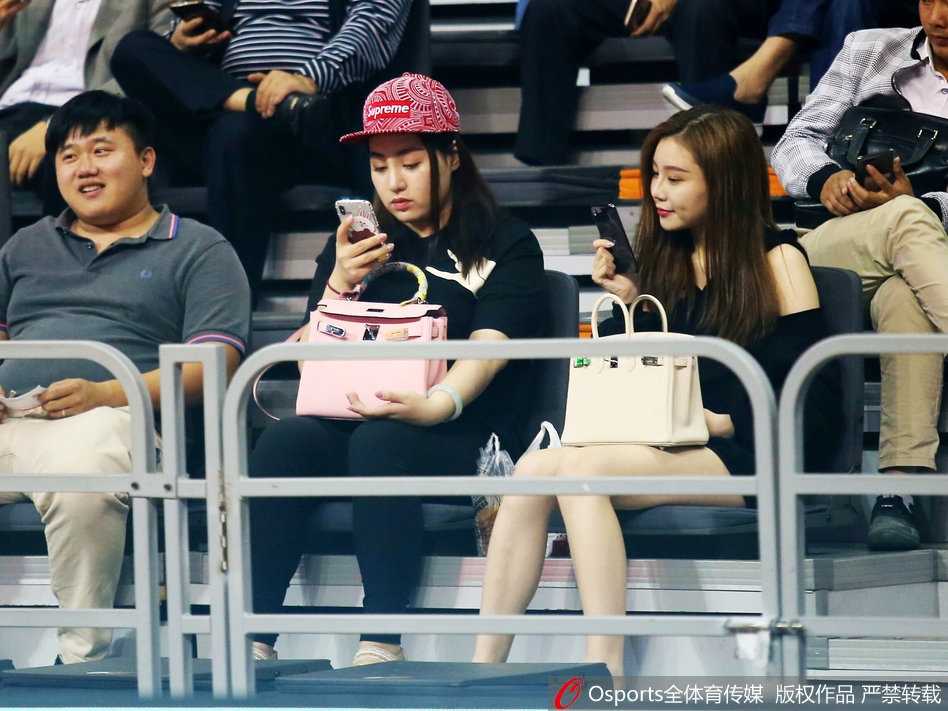 粤疆大战场边的那一抹温柔亮色 一位面容清秀的女球迷坐在场边,目光越过喧嚣,专注地望向赛场方向,仿佛与周遭的紧张气氛隔绝。