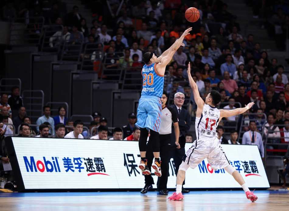 新疆队外援亚当斯面对赵睿的贴身紧防，手腕轻抖送出一记精妙的背后传球，眼神狡黠而专注，试图撕开广东队的防线。