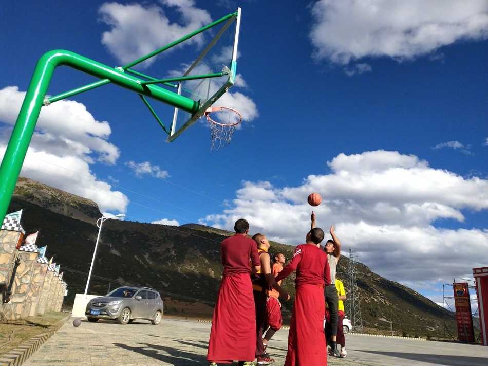 红尘之外的篮球梦,稻城蚌普寺僧袍下的灵动身影 球场上,两名喇嘛正激烈地争抢篮板,僧袍的宽大袖口随风扬起,露出他们结实的手臂。他们的眼神紧盯着篮球,那股认真劲儿丝毫不亚于专业运动员。