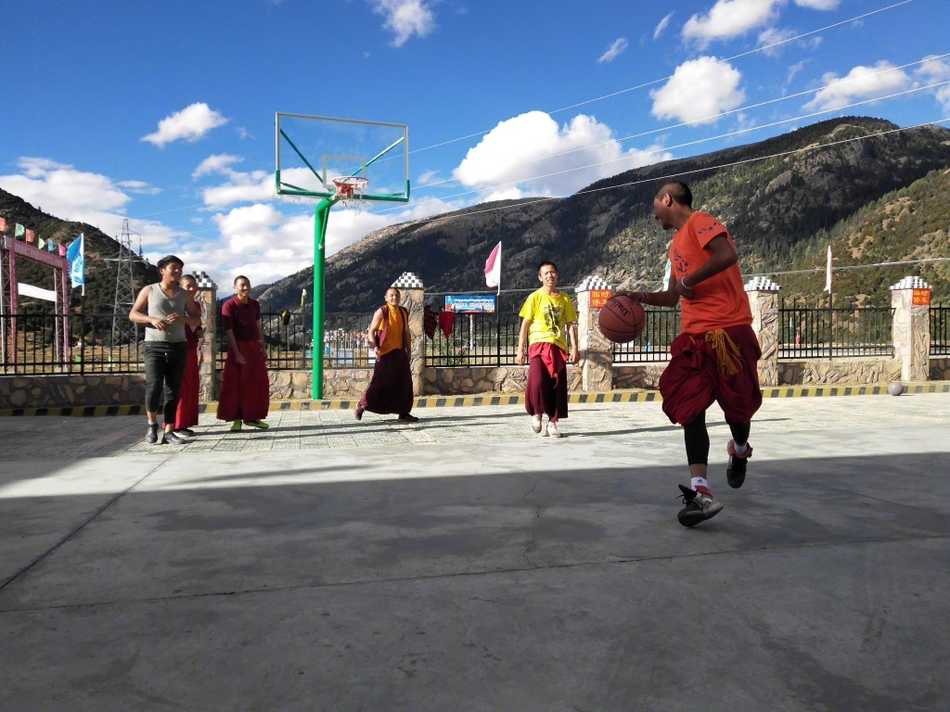 红尘之外的篮球梦,稻城蚌普寺僧袍下的灵动身影 一名年轻的喇嘛正准备投篮,他双腿微曲,双手持球举过头顶,僧袍的衣摆垂落在地。在他身后,是连绵的雪山和湛蓝的天空,构成一幅动静结合、充满禅意的画面。