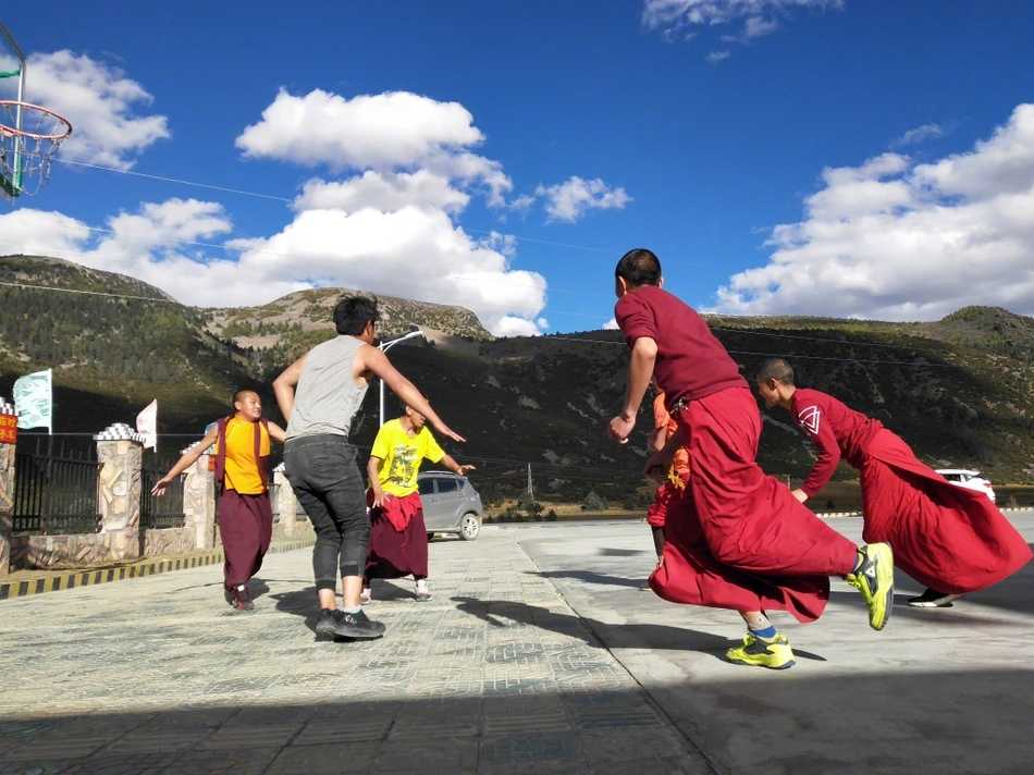 红尘之外的篮球梦,稻城蚌普寺僧袍下的灵动身影 夕阳的余晖洒在简陋的水泥地球场上,给几位围在一起商讨战术的喇嘛镀上了一层温暖的金边。他们用手比划着,表情认真而放松,仿佛在进行一场神圣的仪式。