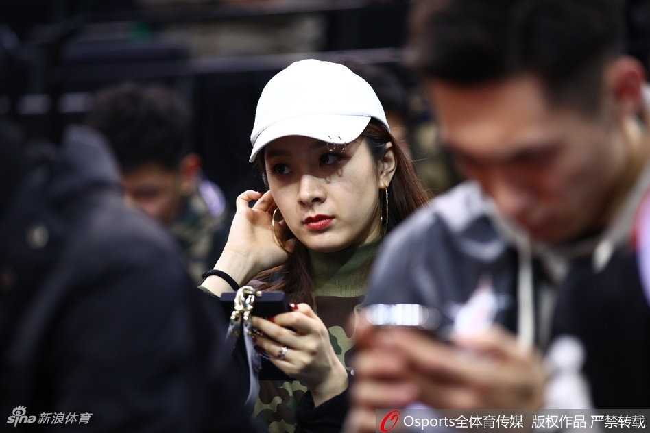 翟晓川携爱妻甜蜜亮相全明星 场边伉俪情深成星锐赛别样风景 杨思雨侧身面对镜头,嘴角带着浅浅的笑意,翟晓川则凝视着赛场方向,两人沉浸在全明星周末的欢快氛围中,身后是座无虚席的热烈球场。