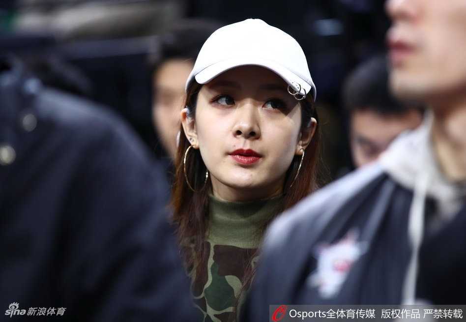 翟晓川携爱妻甜蜜亮相全明星 场边伉俪情深成星锐赛别样风景 杨思雨在观众席上露出灿烂的笑容,眉眼弯弯,气质温婉大方。翟晓川则在一旁专注地看着她,眼神中充满爱意,背景是CBA全明星赛场的灯光与人群。