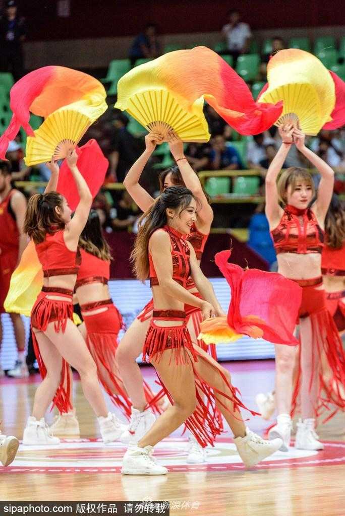 姑娘们围成一个半圆，手中的折扇完全展开，拼接成一道绚丽的扇形屏风，她们高抬腿的动作充满活力，脸上洋溢的笑容比手中的扇花还要灿烂。