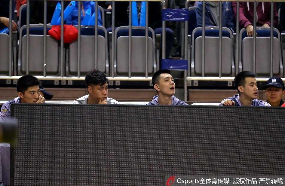 贺天举久违现身替补席,辽宁神射静待归来 贺天举身穿休闲外套双手插兜,在场边目睹队友投中三分