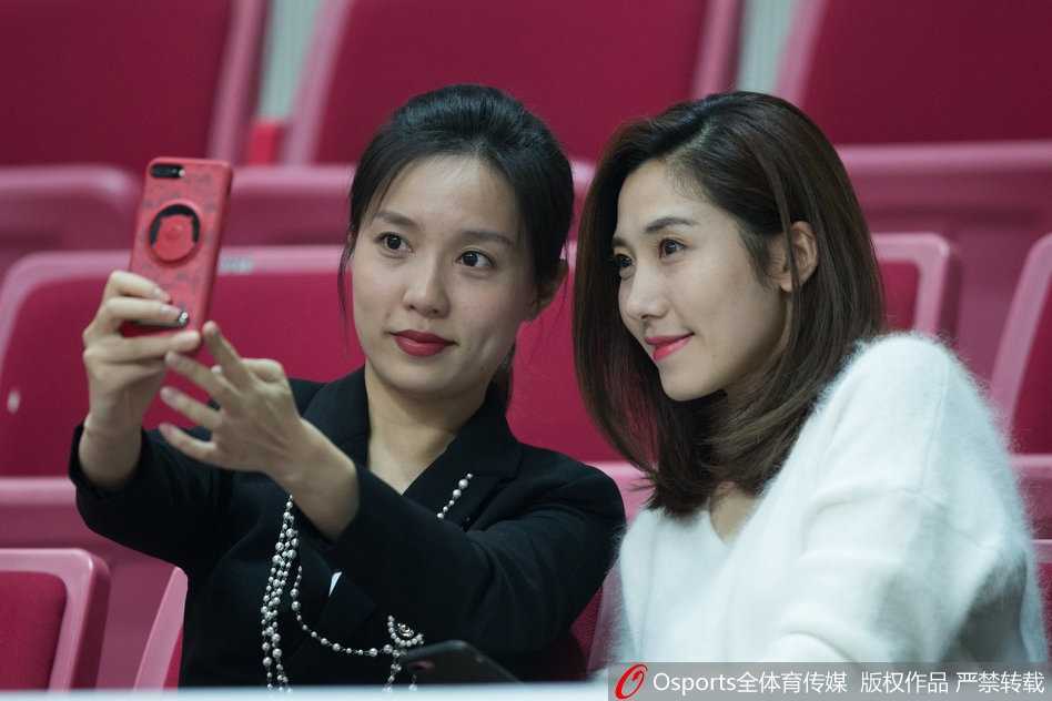 一位长发披肩的女球迷，目光紧紧追随着场内球员的动向，脸上写满了专注与期待。