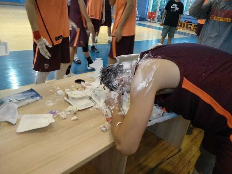 在众人起哄声中，一块蛋糕精准地拍在赵继伟脸上，瞬间奶油飞溅，一旁的周琦探出半个脑袋，咧着嘴偷笑，眼神里满是