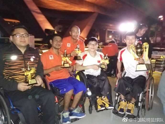 面对身材高大的防守球员，中国队队员眼神坚毅，他一手控制疾驰的轮椅，一手稳稳将球传向篮下的队友，轮椅的轮毂在灯光下折射出拼搏的光芒。