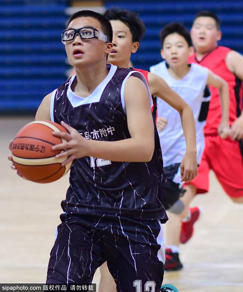 一名身穿蓝色球衣的小球员在三人包夹下依然高高跃起，眼神坚毅地完成投篮，他紧绷的肌肉和舒展的动作定格在空中，展现了篮球少年的蓬勃朝气。