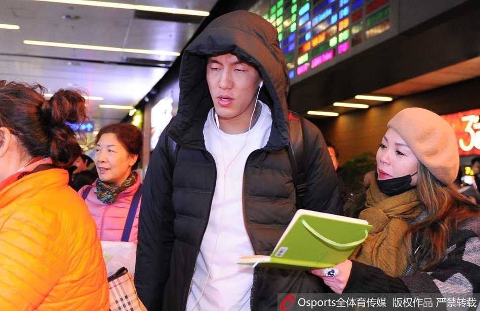 辽宁队中锋韩德君被热情的球迷团团围住，他面带微笑，亲切地俯身为一名小球迷在篮球上签名，场面十分温馨感人。