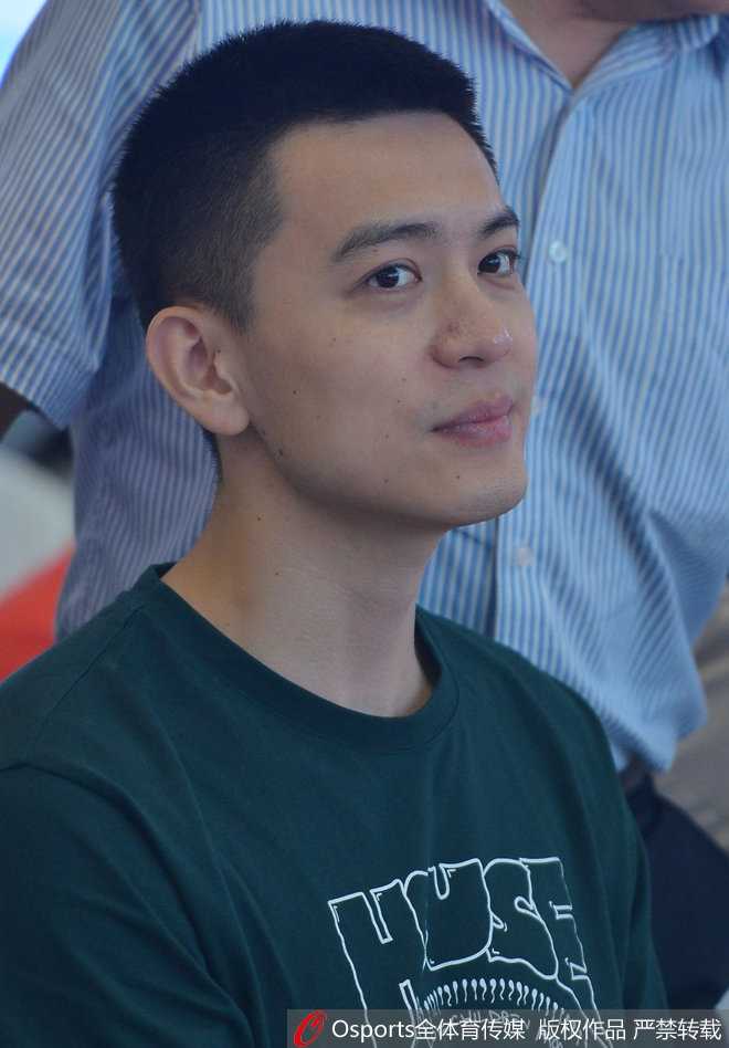 杨鸣在公益活动主背景板前站立，身姿挺拔，现场气氛热烈充满青春活力