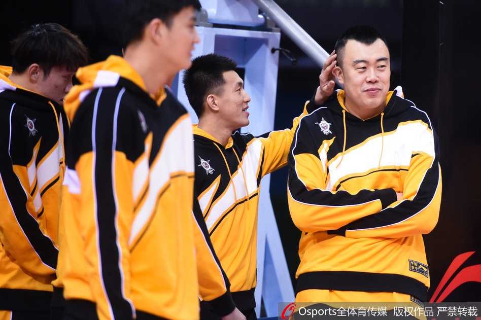 郭艾伦在训练中运球通过，眼神专注中带着一丝狡黠，身后的韩德君张开双臂，似乎正在防守这位灵活的队友，但脸上的笑意却出卖了他此刻轻松的心情。