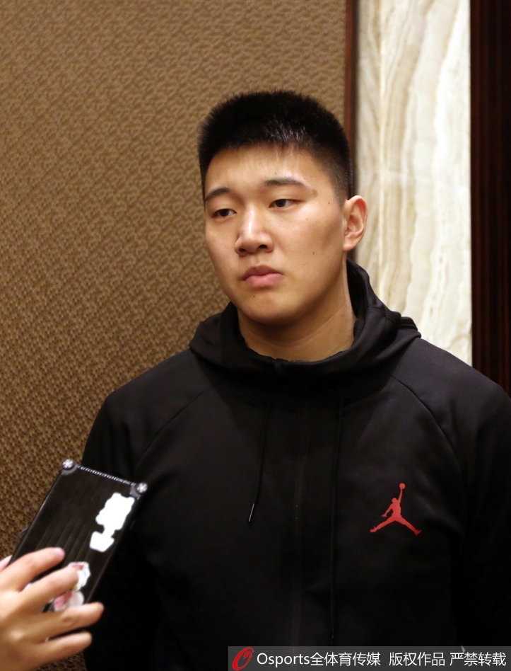 镜头拉近，一位年轻的八一队员正聚精会神地看着手中的资料。背后的背景板印着新赛季的标语，霓虹光斑在他脸上跳跃。这画面仿佛预示着，在主力伤缺的赛季里，这些年轻人将不得不提前接过前辈的枪，在CBA的烽火中加速成长。