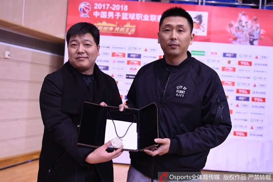 胡雪峰与球迷钱鑫在球场中央握手致意，两人之间传递的不仅是那块精美的金镶玉，更是江苏篮球二十余载的情感传承与球迷文化最真挚的体现。