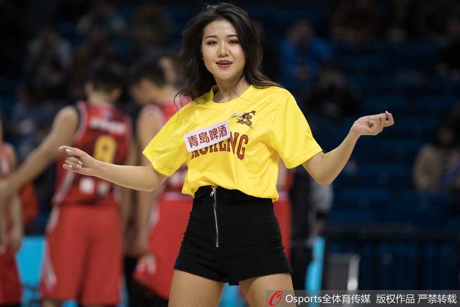 镜头捕捉到一位笑容极具感染力的篮球宝贝特写，她随着音乐的节奏单手叉腰，身体微微侧倾，甜美的笑容和专业的态度让人感受到CBA赛场除了激烈对抗外的另一番魅力。