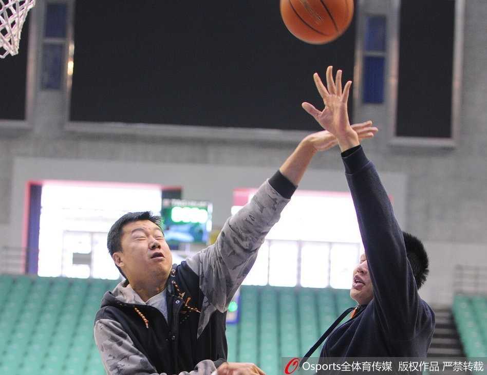 王治郅在场上伸出一根手指，向年轻球员面授机宜，强调防守中协同一致的重要性，球员们认真聆听。