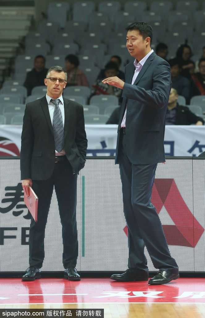 身着运动外套的王治郅，在赛前热身时侧身倾听小兄弟讲话，眼神中满是老大哥的关怀与鼓励，仿佛在传授赛场心得。