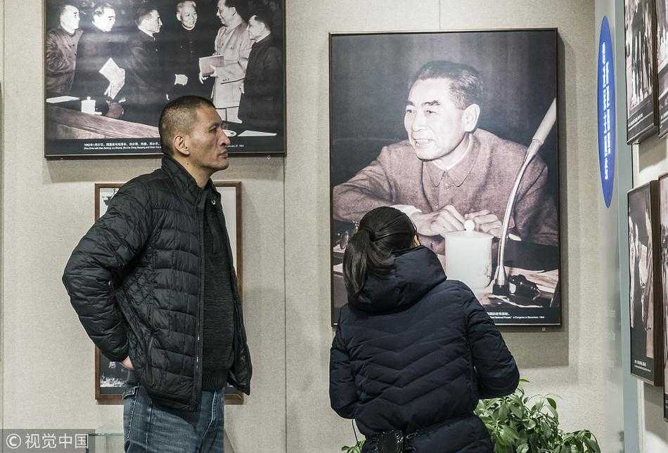 巴特尔与友人一同观看纪念馆内的历史照片，高大的背影在展板前显得格外专注，透着对历史的敬畏